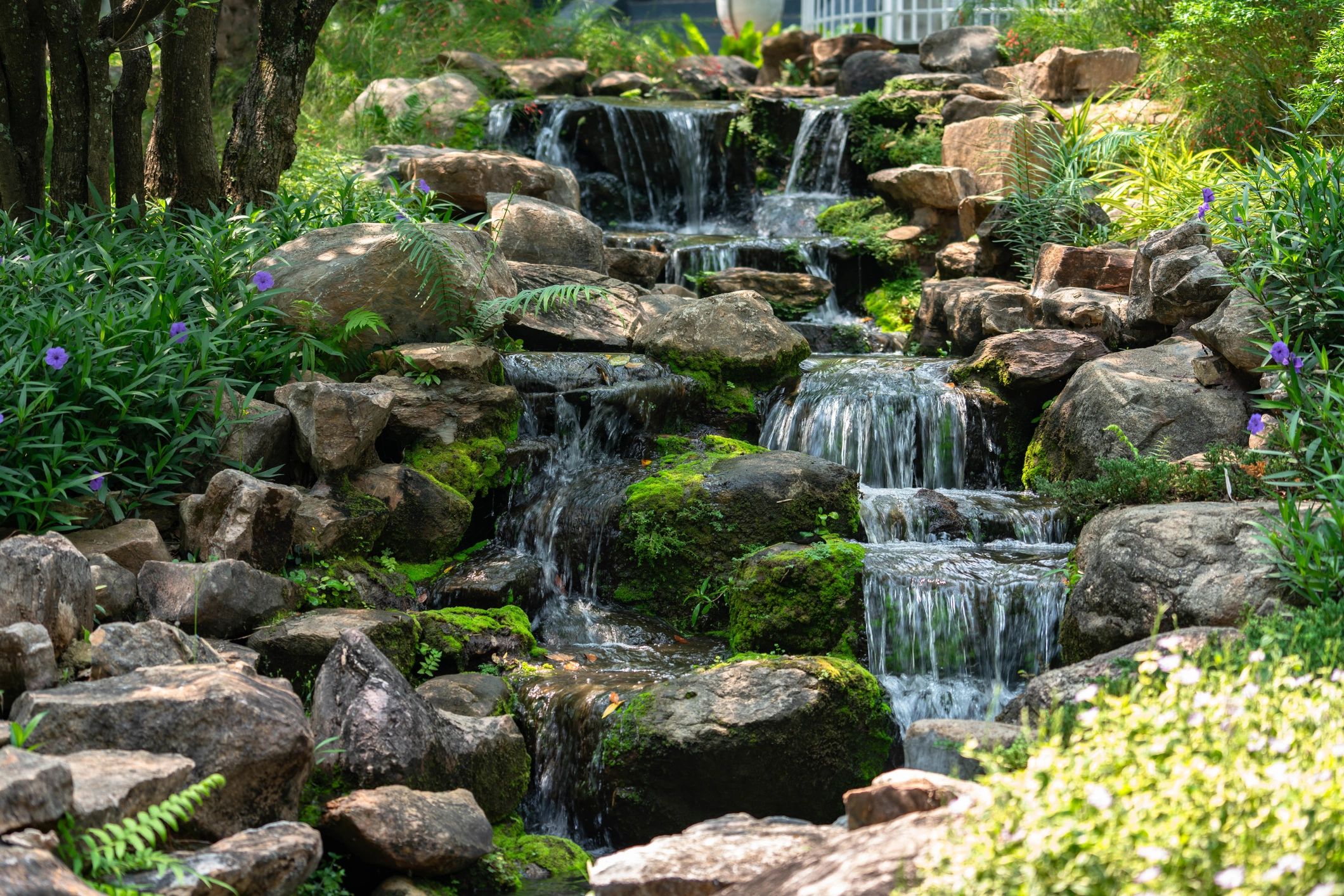 Tiered garden waterfall with rocks and flowers